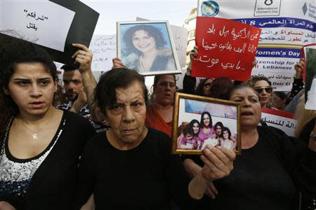 Laila (C), mother of Rola Yacoub, carries a picture of her during a march against domestic violence against women, marking International Women's Day in Beirut March 8, 2014. REUTERS/Jamal Saidi