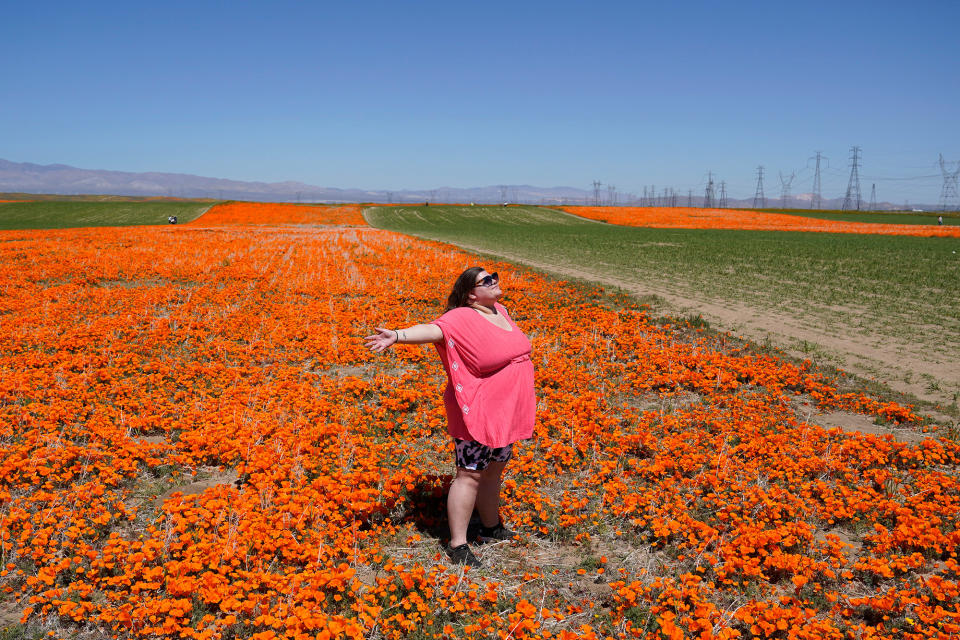 Laila Treadwell, visiting from Atlanta, poses for photos on a field of blooming flowers near the Antelope Valley California Poppy Reserve, on April 10, 2023.