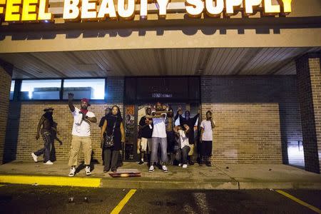 Demonstrators attempt to stop masked individuals from entering a store that had been broken into, during on-going demonstrations to protest against the shooting of Michael Brown, in Ferguson, Missouri, August 16, 2014. REUTERS/Lucas Jackson