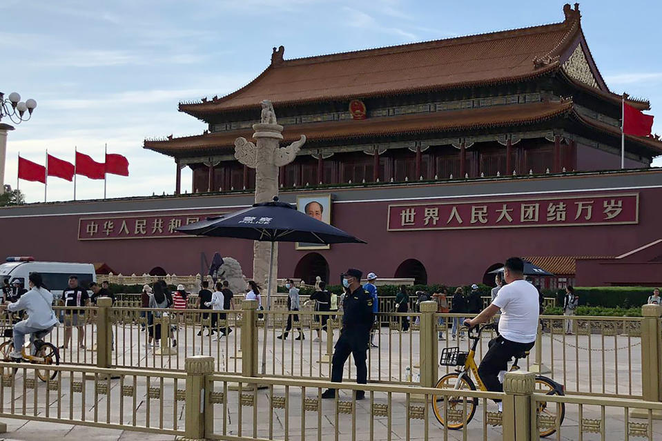 A security person watch over residents passing in front of Tiananmen Gate in Beijing, Sunday, June 4, 2023. China tightened already strict access to Tiananmen Square in central Beijing on Sunday, the anniversary of 1989 pro-democracy protests. (AP Photo/Emily Wang Fujiyama)