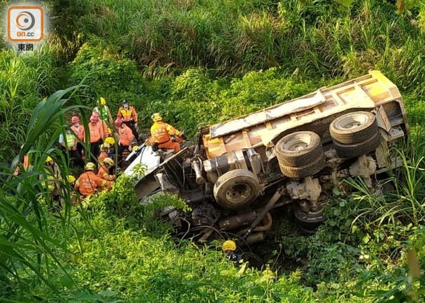 泥頭車衝下山坡後翻側，司機被困。(王鏡文攝)