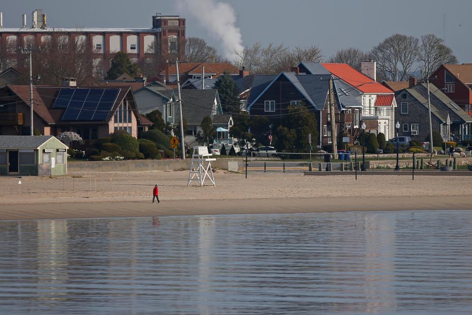 A woman walks along East Beach in the south end of New Bedford.