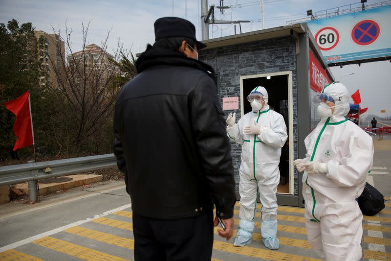 Hospital staff in protective garments talk to a police officer at a checkpoint to the Hubei province exclusion zone at the Jiujiang Yangtze River Bridge in Jiujiang
