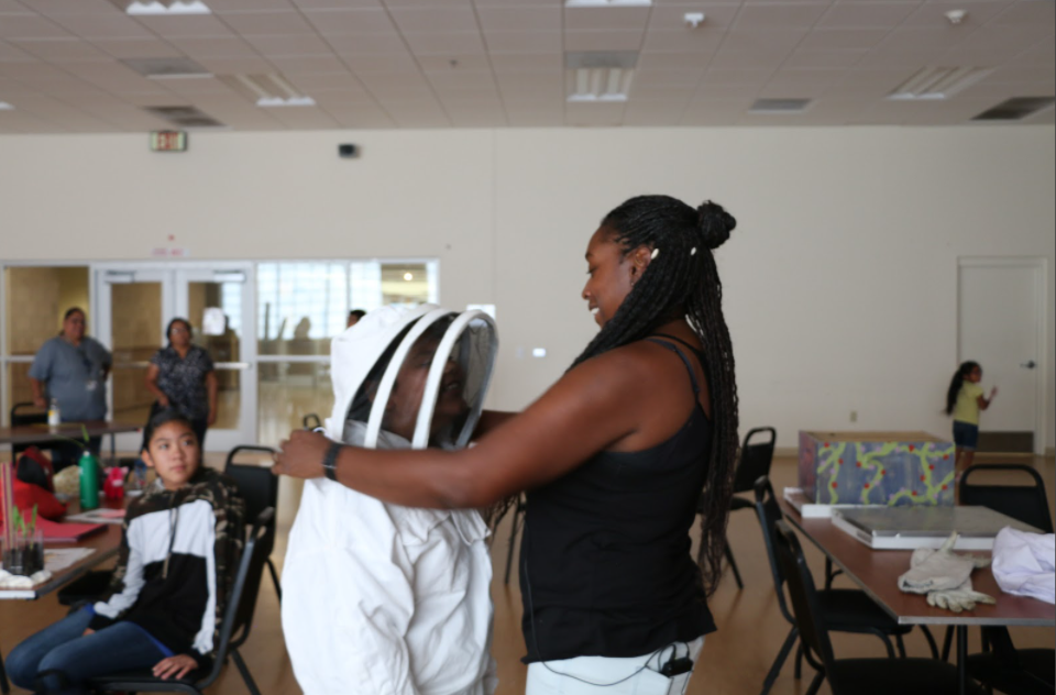 Chanika Forté puts bee suit on a student.