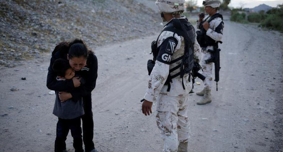 The mother holds her son as she cries as two National Guard soldiers stand nearby.