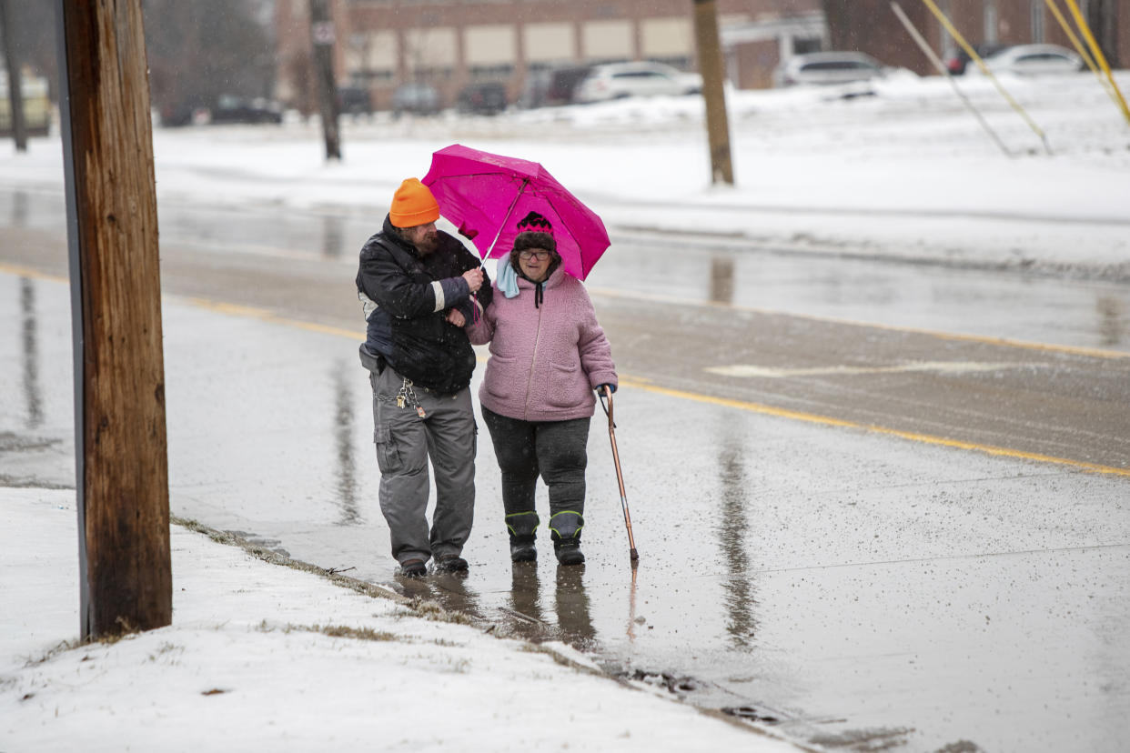 John Poniatowski holds an umbrella over his wife, Chris, as they walk in freezing rain along W. Laketon Avenue in Muskegon, Mich., on Monday, Feb. 27, 2023. The couple said they were walking to the Lakeside Cafe to celebrate Chris' birthday. (Cory Morse/MLive.com/The Grand Rapids Press via AP)