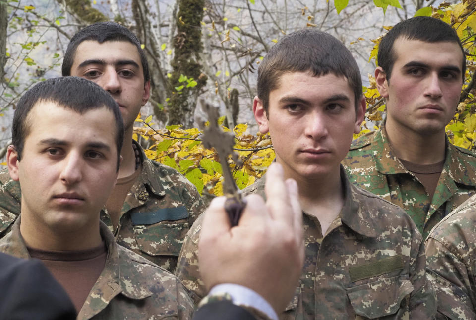 A priest conducts a baptism ceremony for ethnic Armenian soldiers in a military camp near the front line during a military conflict in separatist region of Nagorno-Karabakh, Monday, Nov. 2, 2020. Fighting over the separatist territory of Nagorno-Karabakh entered sixth week on Sunday, with Armenian and Azerbaijani forces blaming each other for new attacks. (AP Photo)