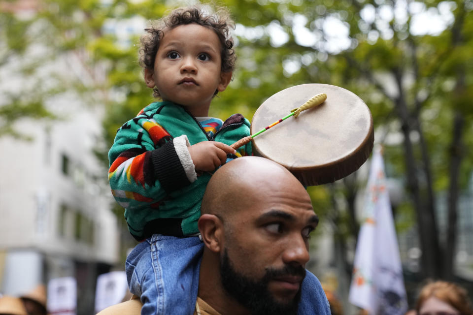 Khalako Lloyd, 2, of the Mandan and Hidatsa tribes, beats on a drum while traveling on father Julius Lloyd's shoulders during a celebratory march for Indigenous Peoples Day, Monday, Oct. 9, 2023, in Seattle. (AP Photo/Lindsey Wasson)