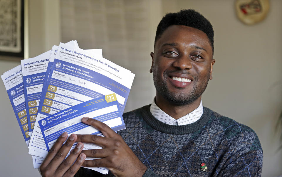 In this photo taken Monday, June 10, 2019, Seattle City Council candidate Shaun Scott, who describes himself as a democratic socialist, displays "Democracy Vouchers" and replacement vouchers designated for his campaign, in Seattle. A first-of-its-kind public campaign finance program in Seattle gives voters vouchers worth $100 to pass on to any candidate they want. Now in its second election cycle, advocates say the program can level the political playing field, although its first round in Seattle showed mixed results. (AP Photo/Elaine Thompson)