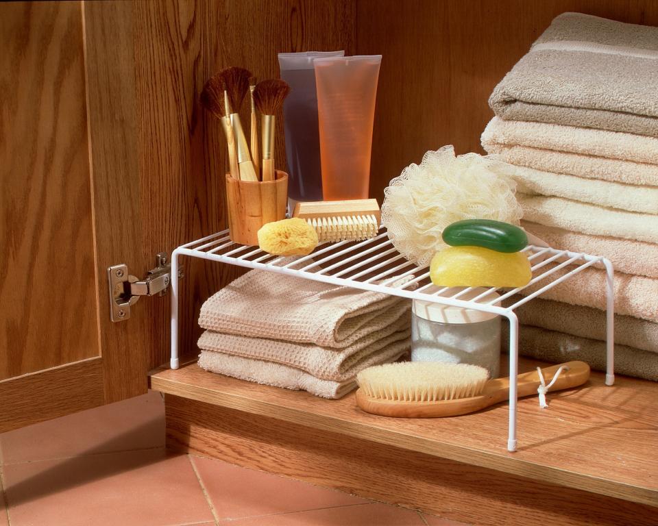 white metal rack in a cabinet holding bathroom items