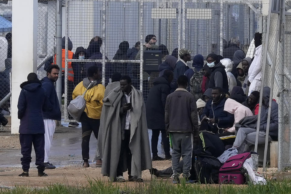 FILE - Migrants stand outside Pournara migrant reception center in Kokkinotrimithia, outside the capital Nicosia, Cyprus, Feb. 9, 2022. Breakaway Turkish Cypriots on ethnically-divided Cyprus must do their share in stemming migrant arrivals, a senior European Union official said Saturday June 18, 2022, as the number of asylum-seekers has shot up significantly so far this year. (AP Photo/Petros Karadjias, File)