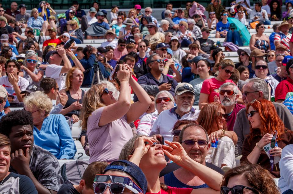 Spectators watch Monday, April 8, 2024, from their seating in the tower terrace area at Indianapolis Motor Speedway as the total solar eclipse begins.