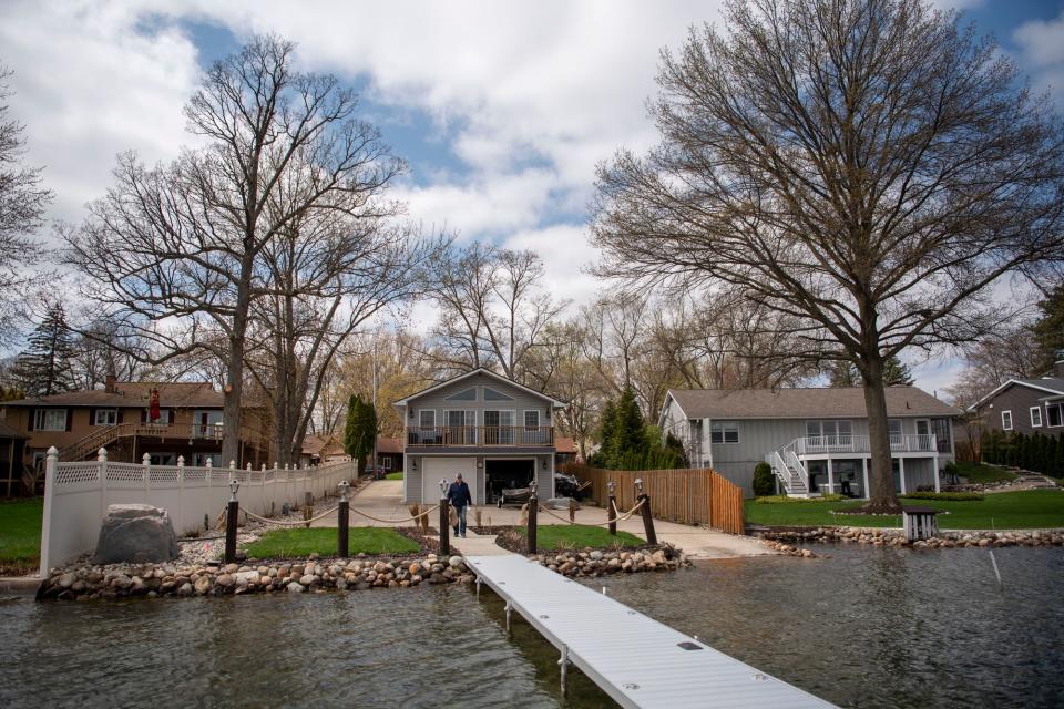 Realtor Frank Roberts walks onto the dock at 265 Lakeshore Drive, which features an island home on Goguac Lake, on Wednesday, May 4, 2022 in Battle Creek, Michigan.