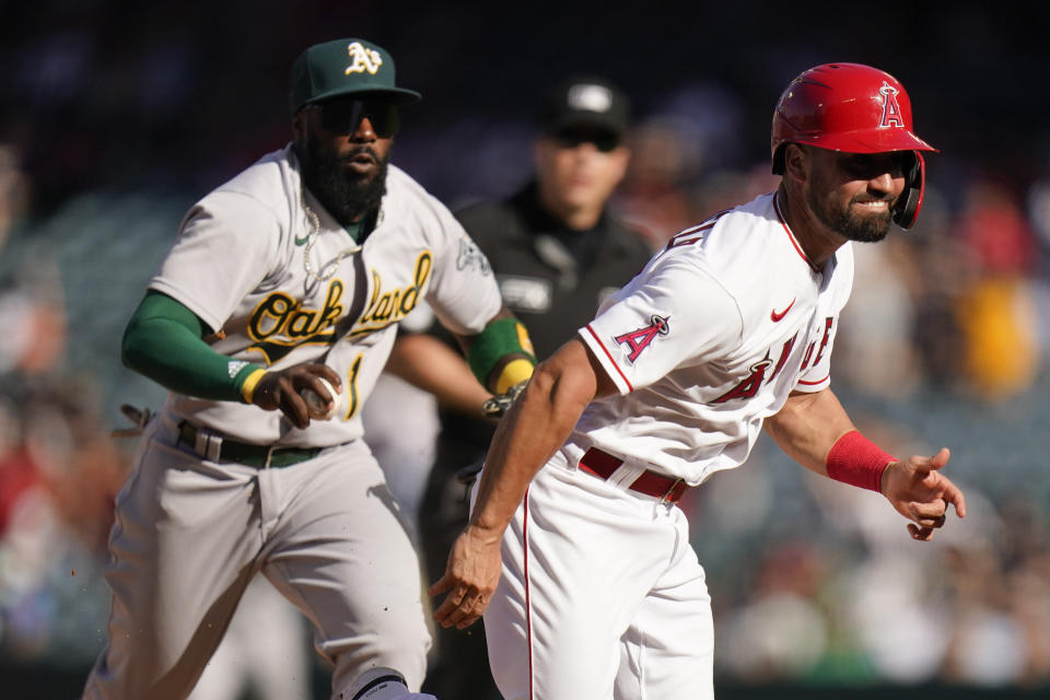 Oakland Athletics' Josh Harrison, background left, chases Los Angeles Angels' Jack Mayfield to tag him out during the 10th inning of a baseball game Sunday, Sept. 19, 2021, in Anaheim, Calif. (AP Photo/Jae C. Hong)