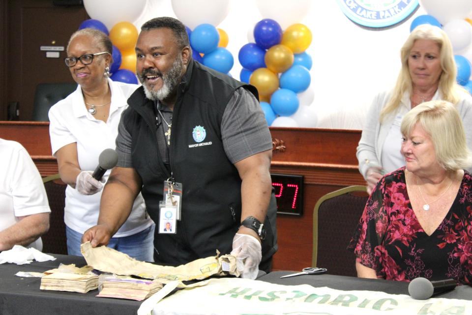 Mayor Roger Michaud laughs as he unravels a 75th-anniversary Lake Park T-shirt at the town's 100th anniversary on Nov. 16, 2023. With him are Centennial Committee members Evelyn Harris Clark (left) and Patricia Leduc and Vice Mayor Kim Glas-Castro.