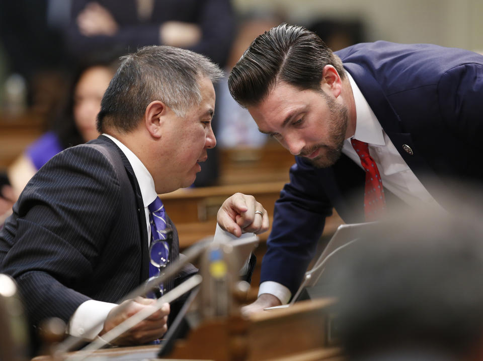 FILE - In this June 13, 2019 file photo, Assemblyman Phil Ting, D-San Francisco, left, chairman of the Assembly Budget Committee talks with Assemblyman Ian Calderon, D-Whittier, right, huddle during the Assembly session, in Sacramento, Calif. California lawmakers approved the state budget that includes an expansion of the state's earned income tax credit. Calderon said Assembly Democrats are having trouble reaching an agreement on conforming the state's tax code to some of the federal changes President Donald Trump signed into law in 2017. Gov. (AP Photo/Rich Pedroncelli, File)