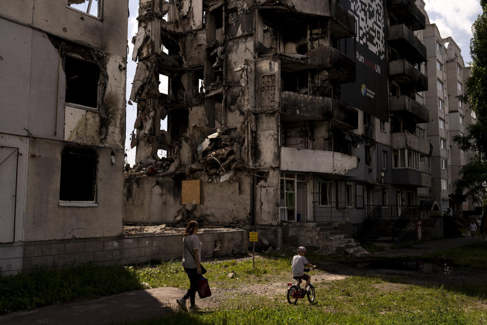 Una mujer y un niño pasan junto a un edificio de apartamentos destruido en ataques rusos en Borodyanka, Ucrania, el miércoles 2 de agosto de 2023. Borodyanka estuvo ocupada por tropas rusas al principio de la invasión de gran escala rusa el año pasado. (AP Foto/Jae C. Hong)