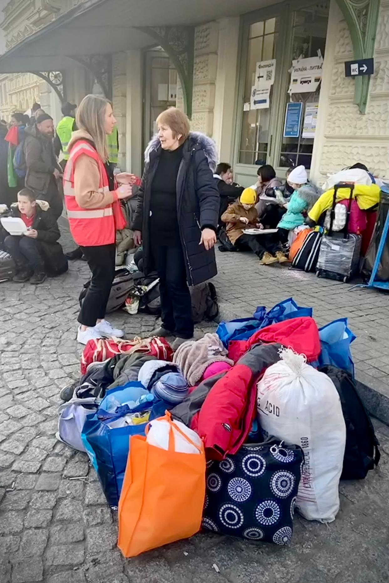 Olga Moroz (left), a city of Jacksonville accountant who was born in Ukraine, spent her vacation greeting refugees at a train station in Poland. In this photo, she talks to one of the refugees while the woman's twin 3-year-old grandchildren sleep on all the possessions they have after fleeing Ukraine.