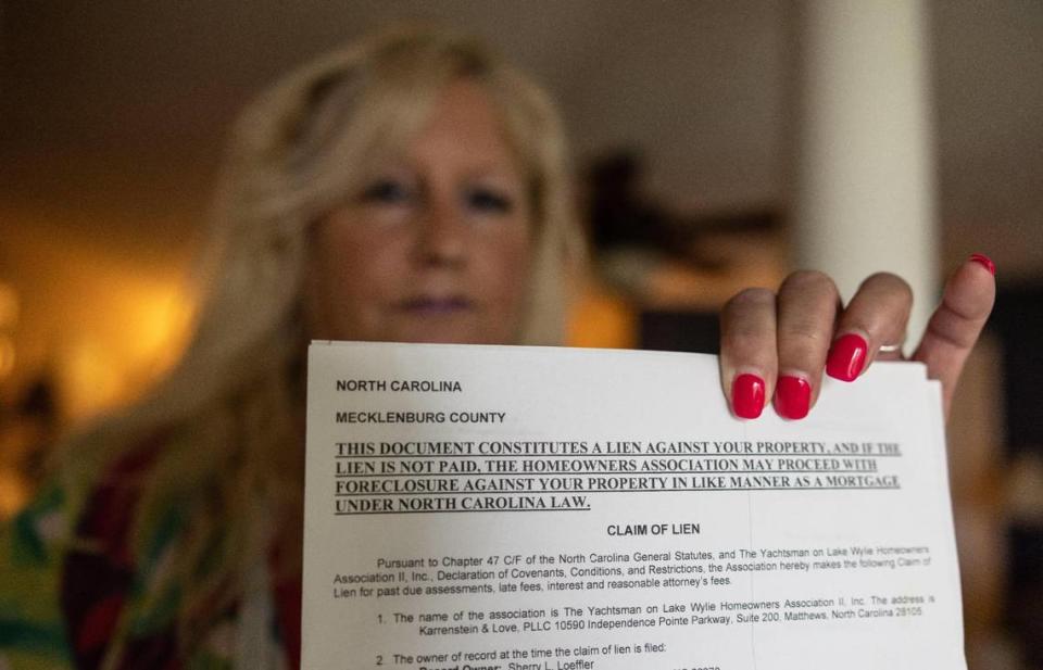 Sherry Loeffler holds the notice of the lien that her HOA put on her home after fining her nearly $12,000 - over windows that she contends they approved. A Mecklenburg County judge ordered the HOA to remove the lien.