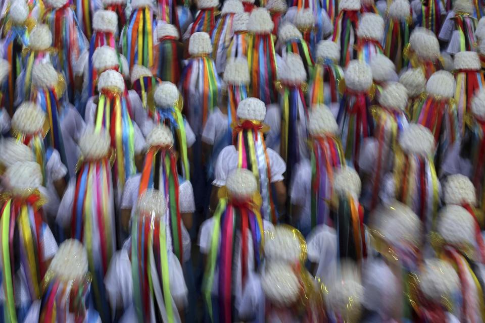 Esta fotografía del 18 de diciembre de 2016, mujeres llevan en la cabeza llamativos gorros con plumas y listones de colores durante la danza del Retumbao dentro de las celebraciones religiosas de la Marujada en honor a San Benedicto en la localidad pesquera de Braganza, en Brasil. A su llegada a una iglesia, algunos participantes pasan el día bailando Lundú, una danza de parejas que se originó en Angola y en la que hay que girar en círculos. (AP Foto/Eraldo Peres)