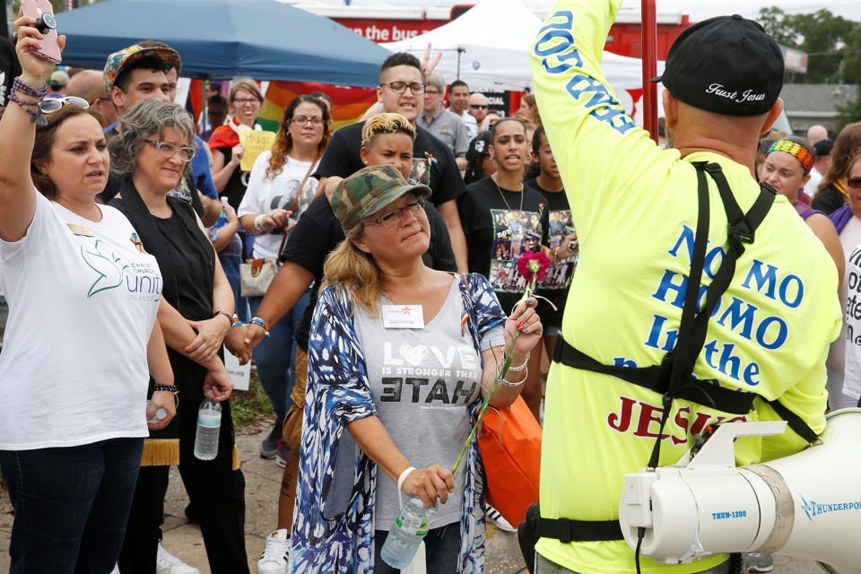 <p>A protester (R) is offered a flower by a guest visiting the memorial outside the Pulse Nightclub on the one-year anniversary of the shooting in Orlando, Florida, June 12, 2017. (Scott Audette/Reuters) </p>