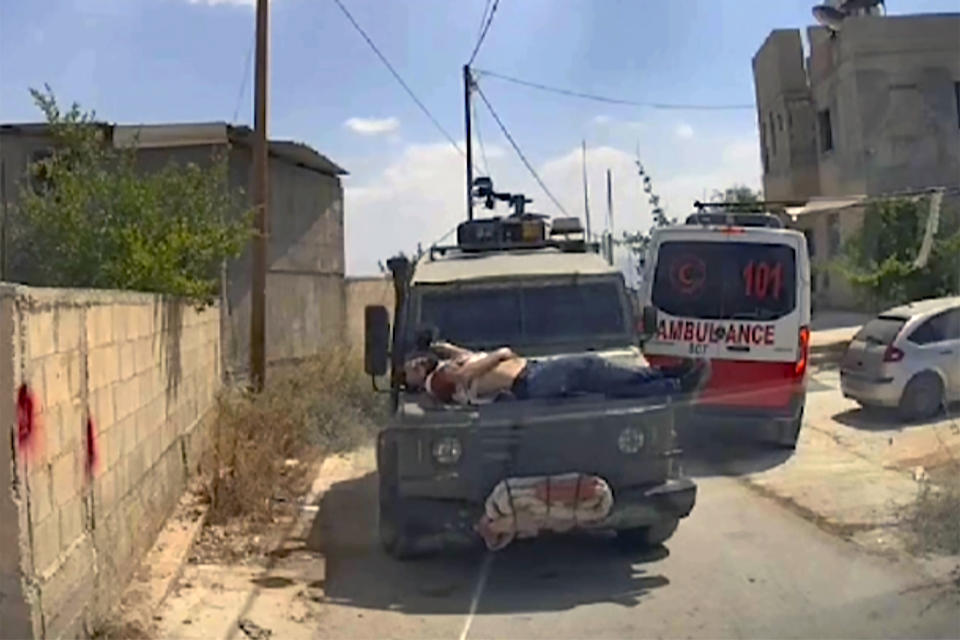 Esta imagen tomada desde una ambulancia muestra a Mujahid Abadi, de 24 años, sangrando por heridas de bala encima del capó de un Jeep de las fuerzas militares israelíes en Yenín, Cisjordania, el sábado 22 de junio de 2024. (Ibn Sina Emergency Center vía AP).