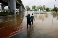 Workers look at a flooded Han River park in Seoul