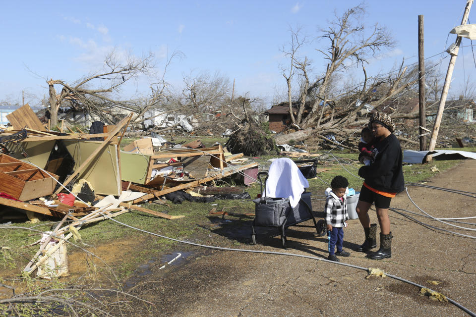 Melanie Childs and her two sons, Major, 2, left, and Milam, 1, stand near what used to be their grandfathers home, Saturday March 25, 2023 in Amory, Miss. Emergency officials in Mississippi say several people have been killed by tornadoes that tore through the state on Friday night, destroying buildings and knocking out power as severe weather produced hail the size of golf balls moved through several southern states. (Thomas Wells/The Northeast Mississippi Daily Journal via AP)