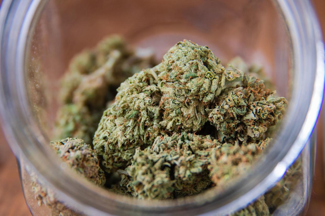 Closeup of several marijuana buds in an opened jar, selective focus, on a table