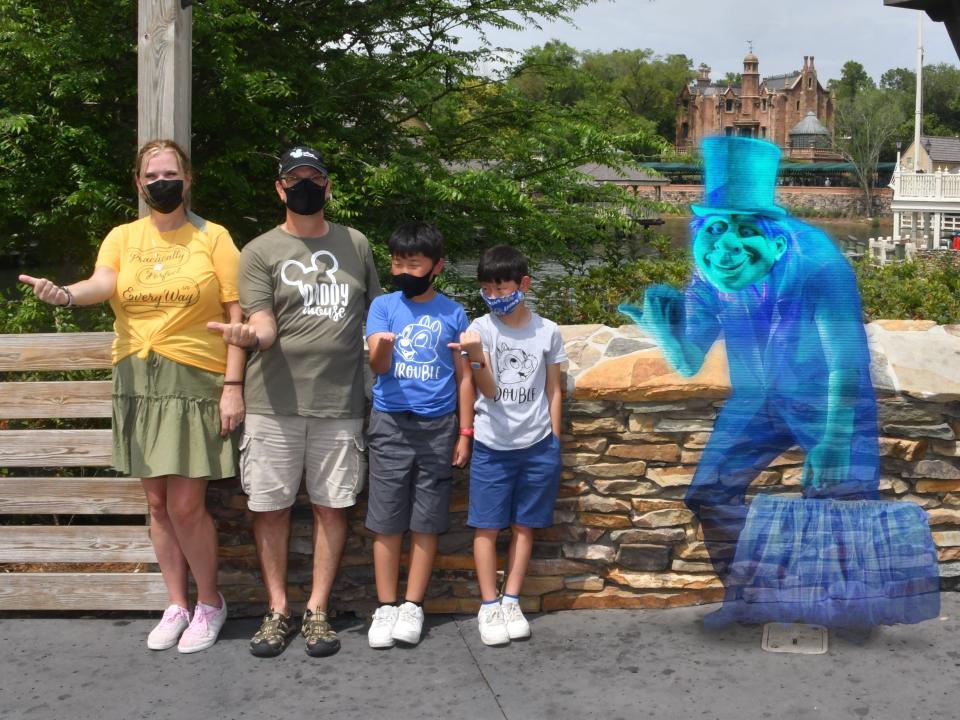 jill and her family posing with a hitchhiking ghost outside of haunted mansion at disney world