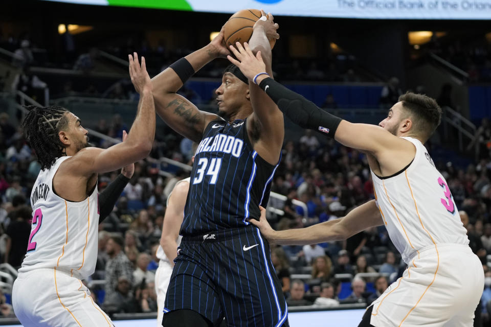 Orlando Magic center Wendell Carter Jr. (34) looks to pass the ball as he is caught between Miami Heat's Gabe Vincent, left, and guard Max Strus, right, during the second half of an NBA basketball game, Saturday, Feb. 11, 2023, in Orlando, Fla. (AP Photo/John Raoux)