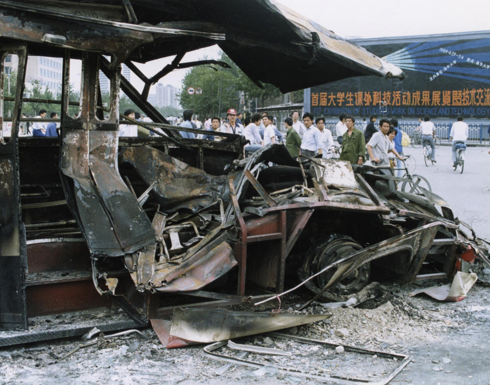 In this June 5, 1989, photo, Beijing residents inspect a bus that was smashed by an armored personnel carrier when the Chinese army fought its way into Tiananmen Square the night of June 3-4 to reclaim the square from student-led demonstrators who had been protesting for democratic reforms for three weeks. (AP Photo/Terril Jones)