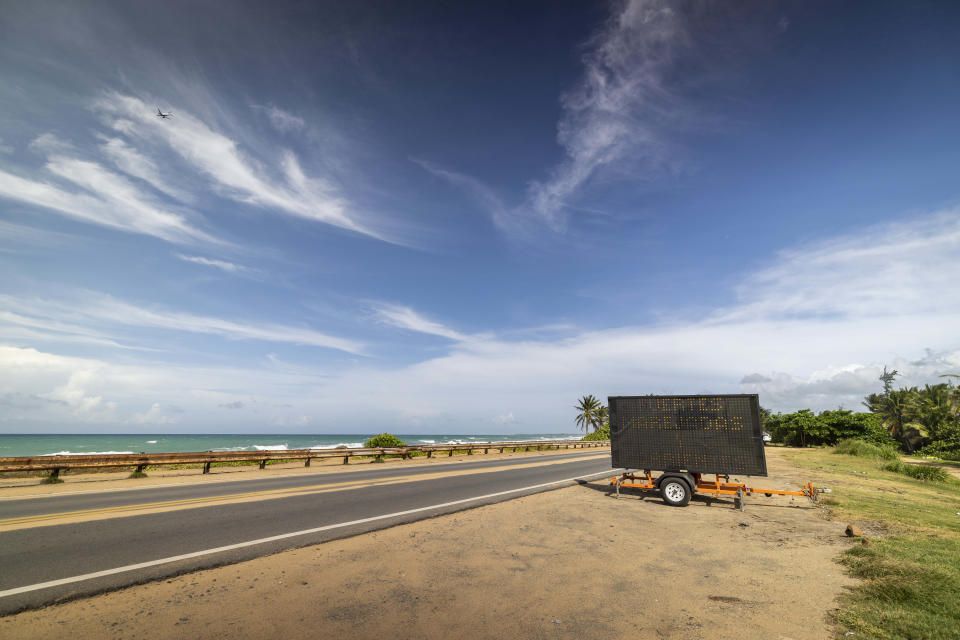 A trailer message board cautions drivers with a message that reads in Spanish: "Strong swells and currents", at the entrance of Loiza, Puerto Rico, Thursday, Sept. 15, 2022. Nearly five years ago Hurricane Maria damaged or destroyed hundreds of thousands of homes and killed an estimated 2,975 people in its sweltering aftermath after razing the island’s power grid. (AP Photo/Alejandro Granadillo)