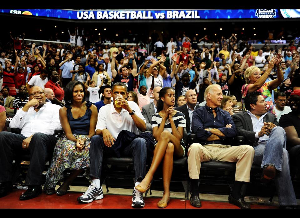 Obama drinks a beer as he sits with his wife Michelle, daughter Malia, and Vice President Joe Biden, as the U.S. Senior Men's National Team and Brazil play during a pre-Olympic exhibition basketball game at the Verizon Center on July 16, 2012 in Washington, D.C. (Photo by Patrick Smith/Getty Images)