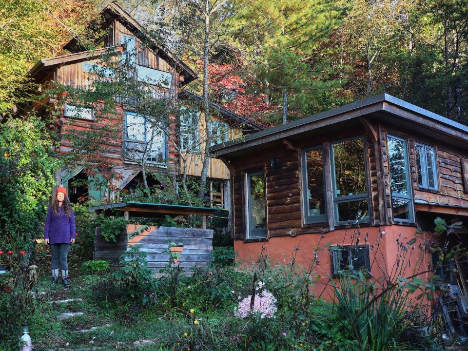 Natalie Bogwalker und das Blockhaus, das sie im Laufe der Jahre gebaut und erweitert hat. - Copyright: Photo courtesy of Wild Abundance.