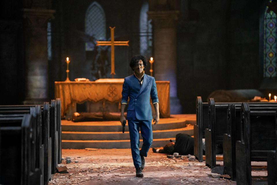 John as Spike walking through a church with a gun