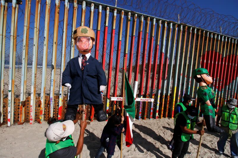 Migrants and members of civil society hold pinatas during a protest in Tijuana