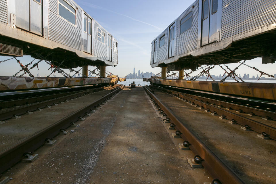 One World Trade Center in Manhattan is visible from a railroad barge carrying retired 1960s-era R-32 subway cars through New York Harbor in New York, on Wednesday, June 15, 2022. Crews are taking the old subway cars to an Ohio scrapyard as the MTA installs new R-179 train cars into the city's sprawling subway system. (AP Photo/Ted Shaffrey)