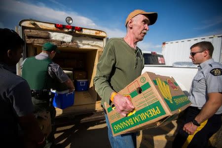 Volunteers help carry food into a community centre in Anzac where residents of Fort McMurray have assembled after their city was evacuated due to raging wildfire, May 4, 2016. REUTERS/Topher Seguin