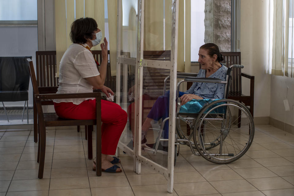 Rafka Nassim, 71, right, meets with her daughter Claudette Rizk through a plastic barrier to avoid contracting the coronavirus, at the Social Services Medical Association, a rehabilitation hospital and nursing home in the northern city of Tripoli, Lebanon, Thursday, June 10, 2021. With virtually no national welfare system, Lebanon’s elderly are left to fend for themselves amid their country’s economic turmoil. (AP Photo/Hassan Ammar)