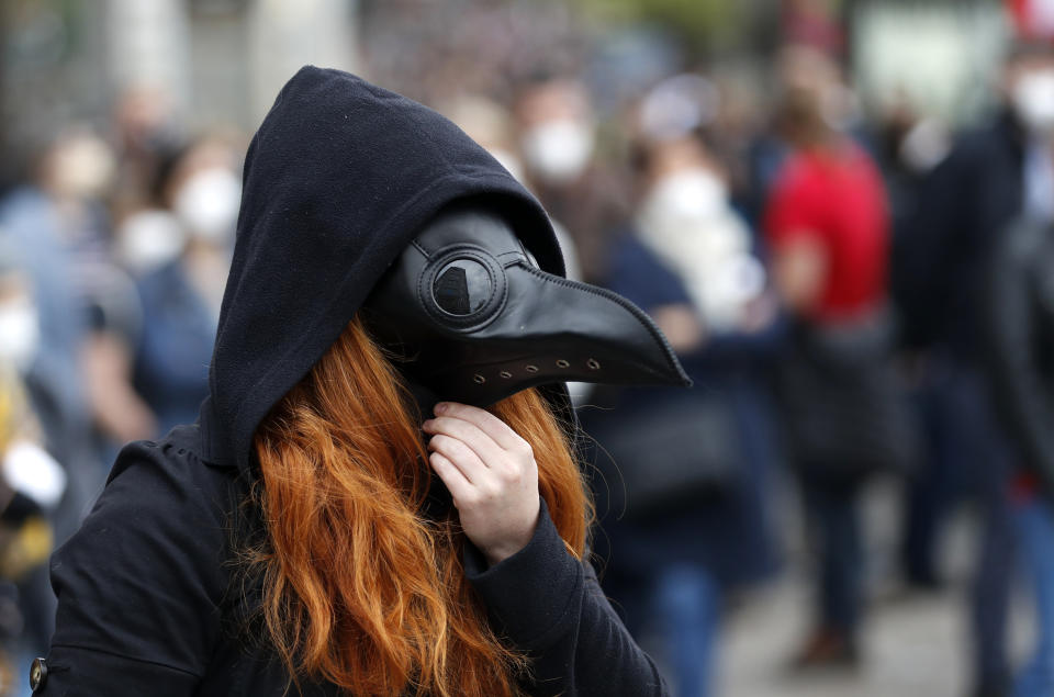 A woman adjusts her mask during a demonstration in Prague, Czech Republic, Thursday, April 29, 2021. Thousands of Czechs have rallied in the capital against President Milos Zeman, accusing him of treason for his pro-Russian stance over the alleged participance of Russian spies in a Czech huge ammunition explosion. (AP Photo/Petr David Josek)