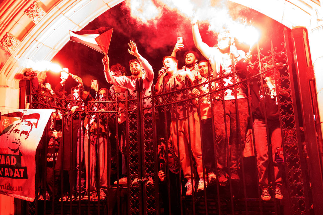  Pro-Palestinian protesters, some holding flares, climb a fence during a demonstration at the City College Of New York.