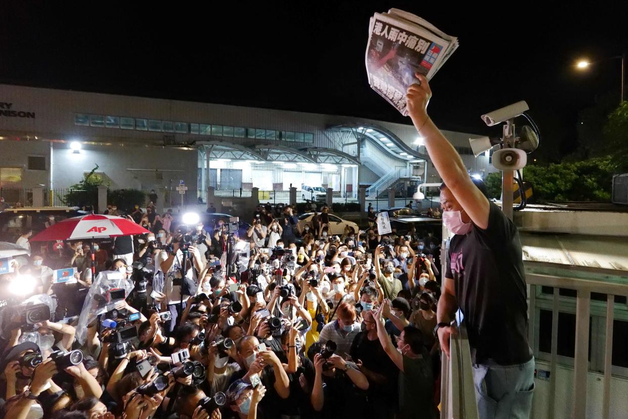 An Apple Daily journalist holds freshly-printed copies of the newspaper’s last edition to be distributed to supporters gathered outside their office in Hong Kong early on 24 June  (AFP via Getty Images)