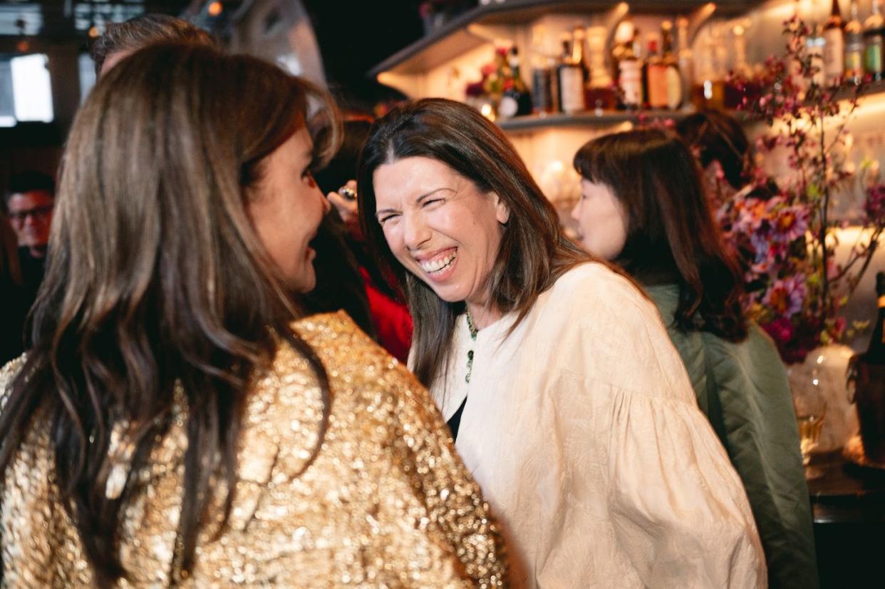 a person kissing another woman's cheek