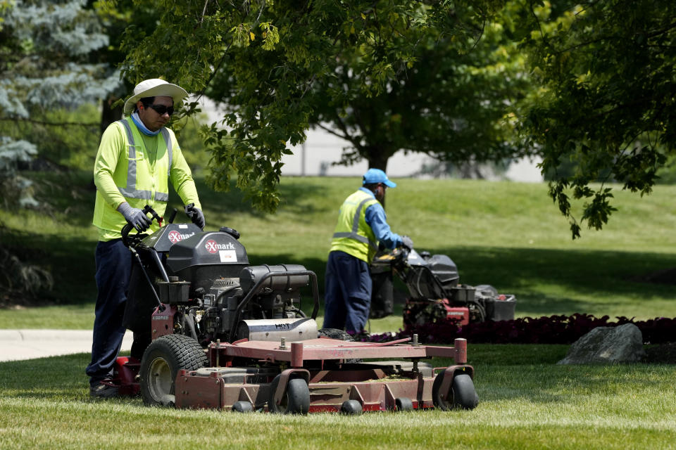 Workers cut grass during hot weather in Riverwoods, Ill., Monday, June 17, 2024. (AP Photo/Nam Y. Huh)