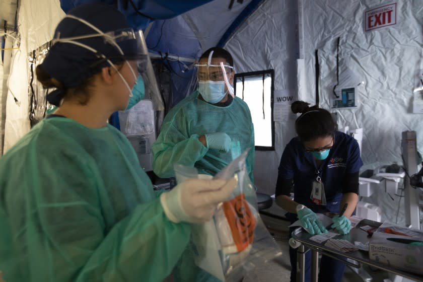 LOS ANGELES, CA - APRIL 21: During the coronavirus global pandemic Sandy Valle, RN, left, Javier Gonzalez, EMT, middle, and Michelle Kim, RN, right, are working inside the triage tent at Martin Luther King, Jr., Community Hospital on Thursday, April 27, 2020 in the Willowbrook neighborhood located in South Los Angeles, CA. The international Medical Corps brought in this tent and it was places outside the Emergency Department at MLKCH. It's for ambulatory patients that have fever, cough, and shortness of breath, potential covid-19 symptoms. Dr. Oscar Casillas says, "We use the large tent to create more space and greater space between patients." (Francine Orr / Los Angeles Times)