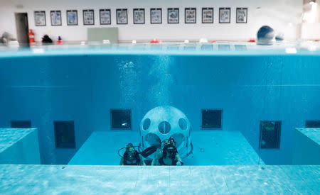 Belgians Florence Lutje Spelberg and Nicolas Mouchart dive next to "The Pearl", a spheric dining room placed 5 metres underwater in the NEMO33 diving center, one of the world's deepest pools (33 metre/36 yards) built to train professional divers, before enjoying a meal inside, in Brussels, Belgium January 30, 2017. Picture taken January 30, 2017 REUTERS/Yves Herman