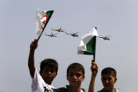 Algerian boys wave their national flag during a military parade to mark the 60th anniversary of Algeria's independence, Tuesday, July 5, 2022 in Algiers. Algeria is celebrating 60 years of independence from France with nationwide ceremonies, a pardon of 14,000 prisoners and its first military parade in years. (AP Photo/Toufik Doudou)