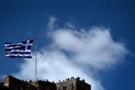 A Greek flag flutters as tourists visit the Acropolis hill in Athens