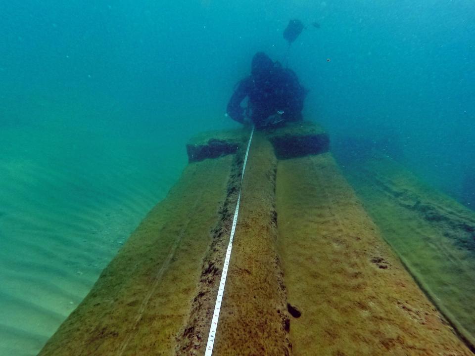 A diver touches an 1,800-year-old beam that sank with a ship in waters off Israel.